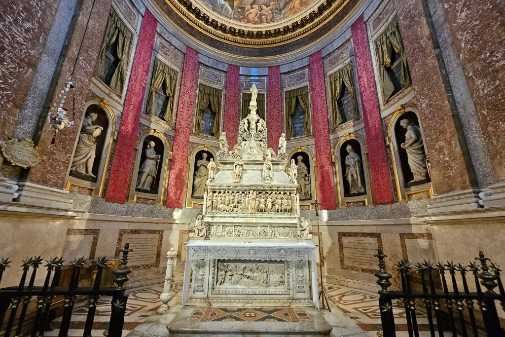 Interior view of the ornate Chapel of San Domenico in Bologna, Italy, featuring the intricately carved Arca di San Domenico (Ark of Saint Dominic), surrounded by red draped walls and marble statues in Renaissance niches. A major highlight of Basilica di San Domenico and one of Bologna’s most important religious and artistic landmarks.