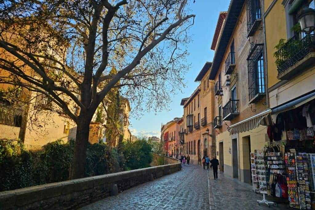 Sunny afternoon on Carrera del Darro, Granada’s most picturesque cobblestone street lined with historic facades, artisan shops, and views of the river – a charming hidden gem in the heart of Granada.