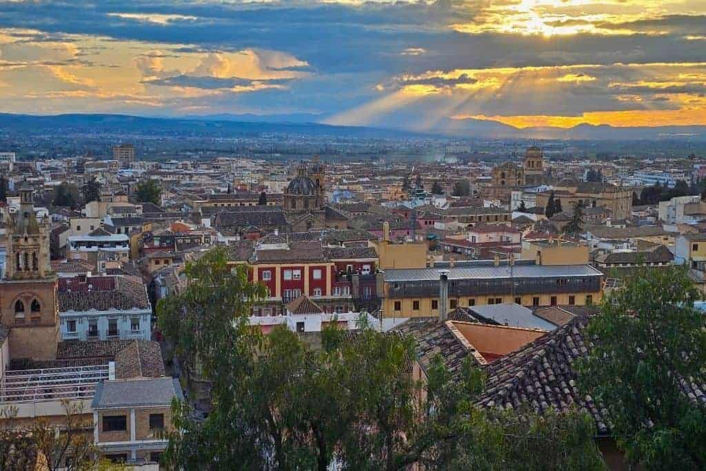 View from Mirador Ojo de Granada during golden hour, overlooking the rooftops and cathedrals of central Granada – a peaceful hidden viewpoint less visited by tourists.