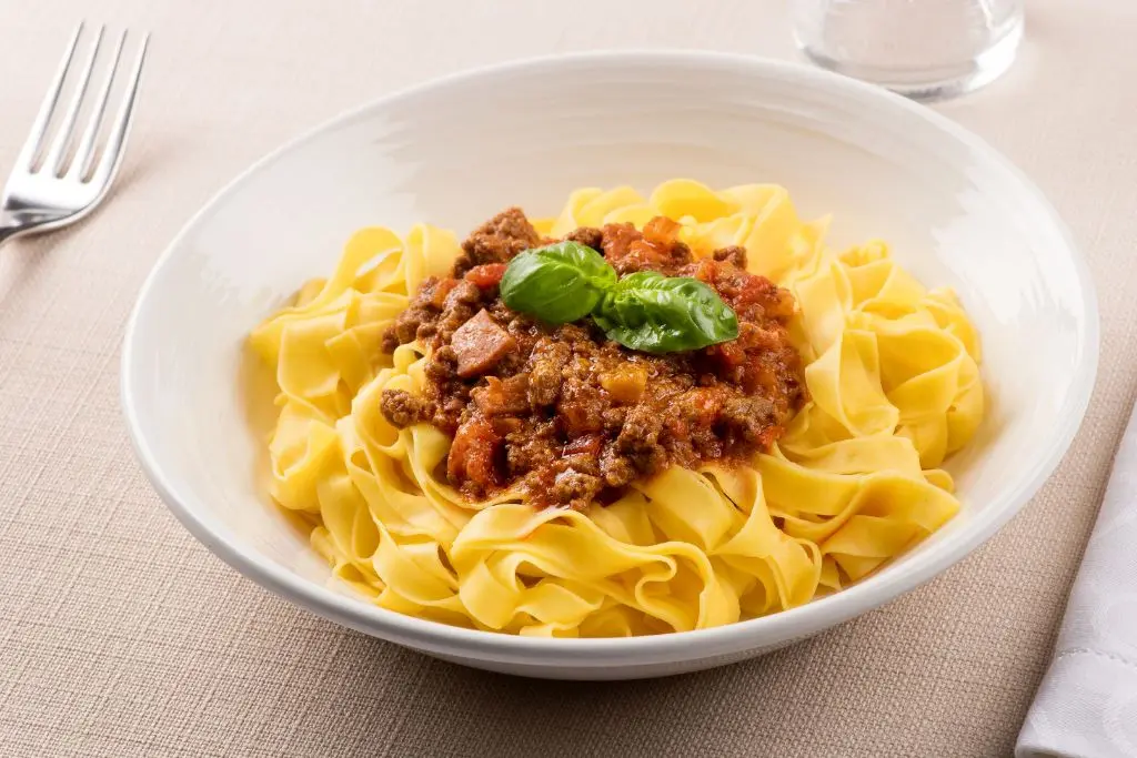 Classic Bologna dish tagliatelle al ragù served in a white bowl—a delicious answer to why food lovers think Bologna is worth visiting.