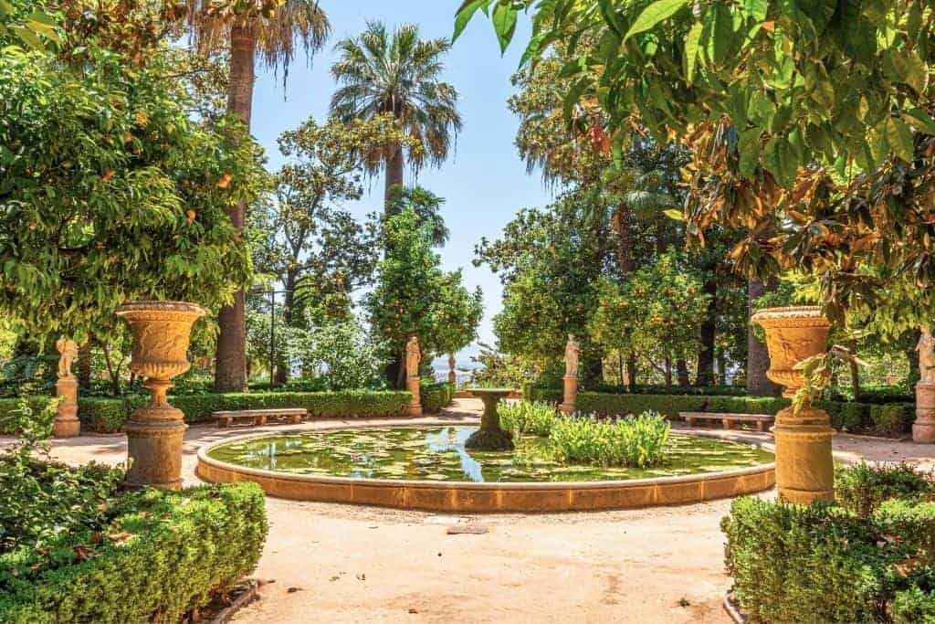 Lush romantic garden with a circular pond and classical statues at Carmen de los Mártires, a peaceful spot near the Alhambra and one of the best free places to visit in Granada.