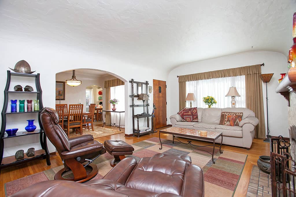 Spacious living room at 3317-3319 Boundary Street in North Park with hardwood floors, comfortable leather recliners, and a wide arched doorway leading into the formal dining area.