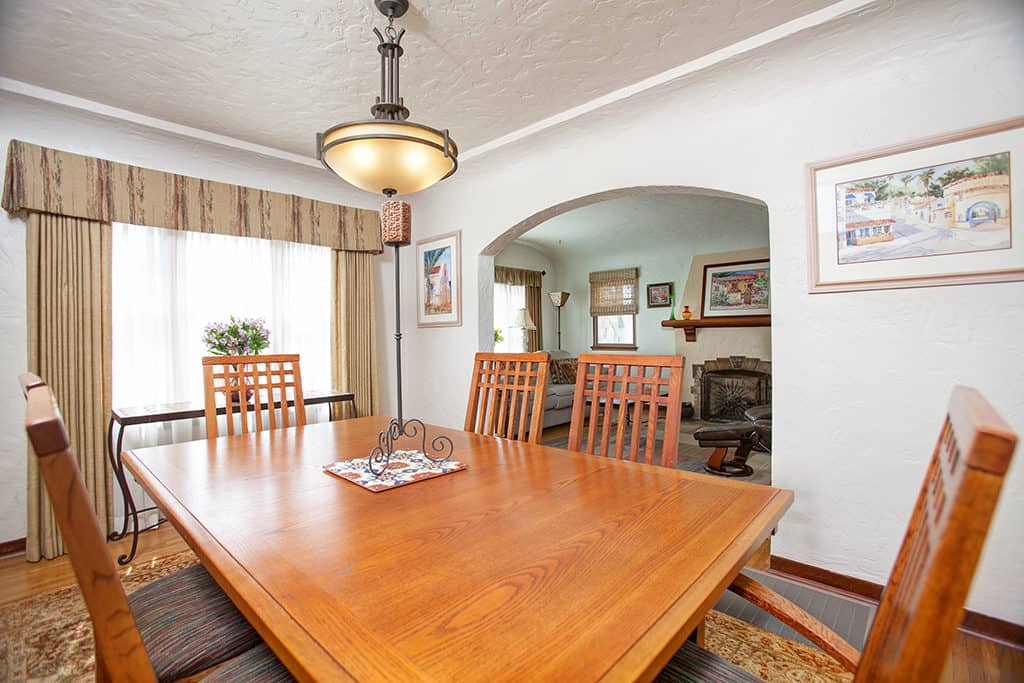 Craftsman-style living room at 3317-3319 Boundary Street in North Park featuring warm wood trim, a decorative fireplace with a wood mantel, and large windows with original architectural detailing.