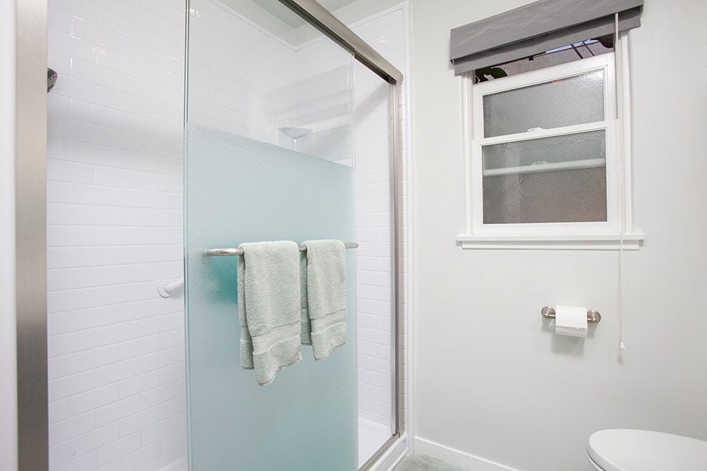 Modern bathroom at 3317-3319 Boundary Street in North Park featuring a walk-in shower with white subway tile, a frosted glass sliding door, and a clean, neutral color palette.