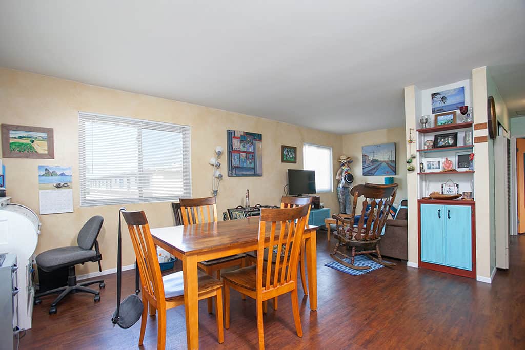Open-concept living and dining space at 3317-3319 Boundary Street in North Park featuring wood-look flooring, a four-person dining set, and a cozy sitting area with a wood rocking chair.
