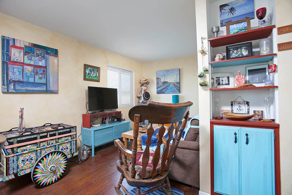 Living area at 3317-3319 Boundary Street in North Park featuring a decorative hand-painted Costa Rican oxcart, a blue media console, and a built-in shelving unit with blue cabinet doors.
