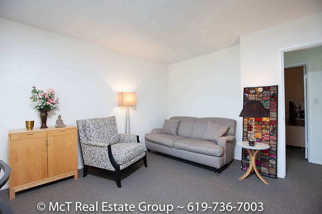 Living room at 3364-66 A Street in South Park featuring a neutral gray sofa and patterned armchair, a light wood storage cabinet, and a colorful tapestry leaning against the wall near a modern side table.