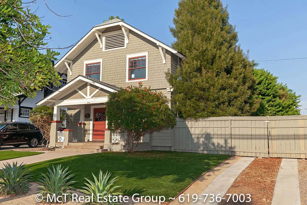 toric two-story Craftsman home with olive-green shingle siding, a gabled front porch, a red entry door, and a manicured lawn at 1511 29th Street in South Park.