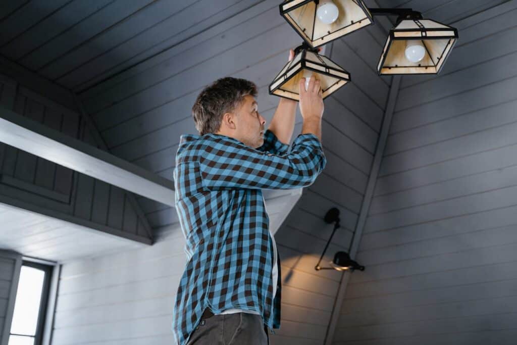 A Man in a Blue Shirt Installing a Light Bulb