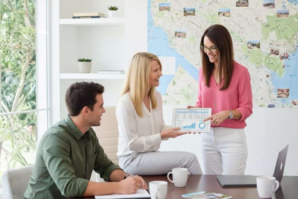 Realtors with their Clients Explaining with a Tablet with Charts and a Map on the Background