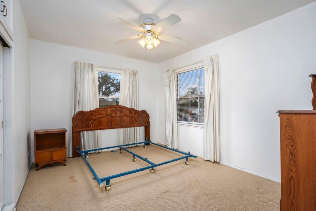 Sunlit secondary bedroom with classic mid-century wooden headboard and ceiling fan at 1751 39th Street, San Diego