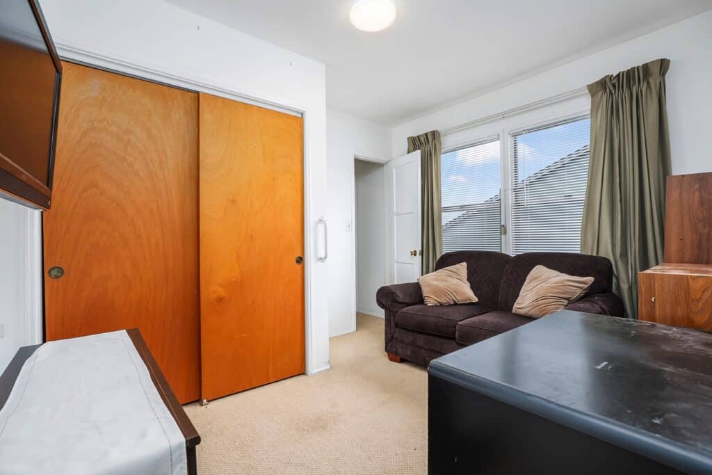 Bedroom featuring ample closet space with wooden sliding doors and a cozy seating area at 1751 39th St, San Diego.
