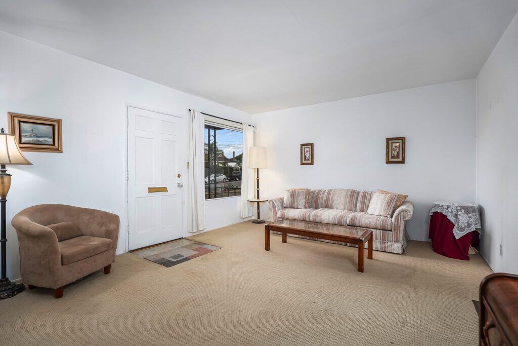 View from the blue front door into the spacious living room of a mid-century home at 1751 39th Street, San Diego, highlighting original architectural details.