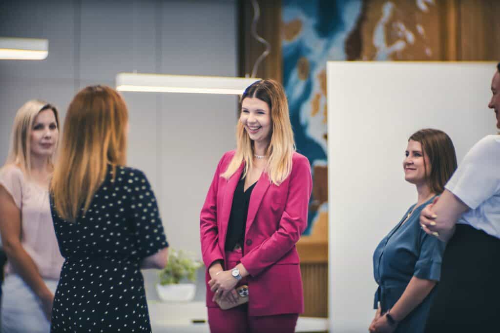a group of women standing in cirlce talking and smiling