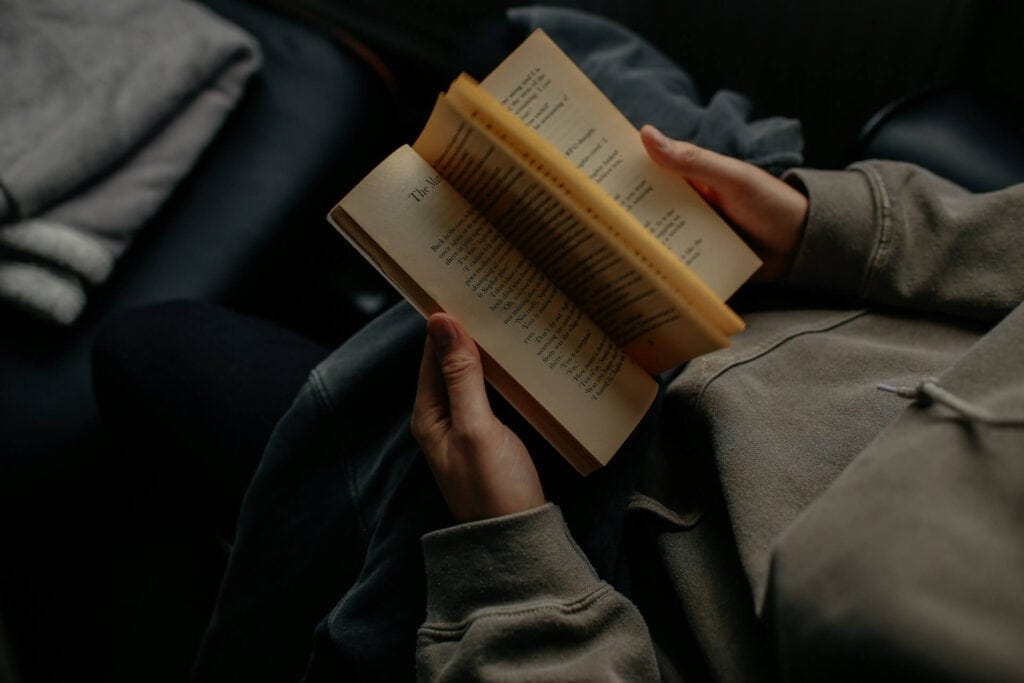 En person med brun tröja sitter och läser en bok om personlig utveckling.
