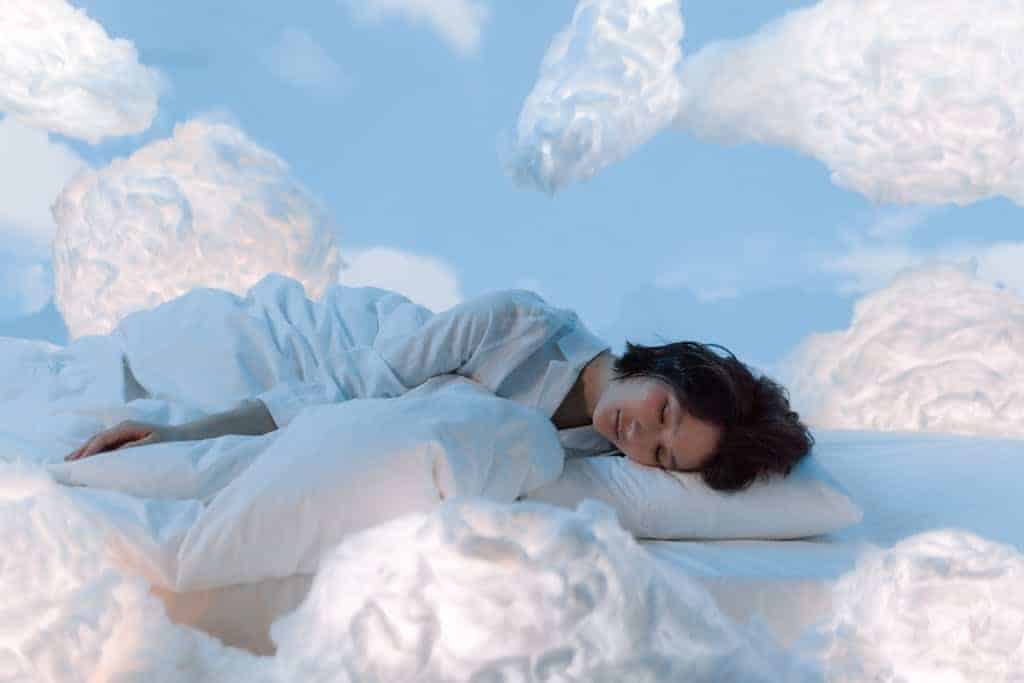 Photo of a Woman Sleeping Near Fluffy Clouds - improve sleep with hypnosis