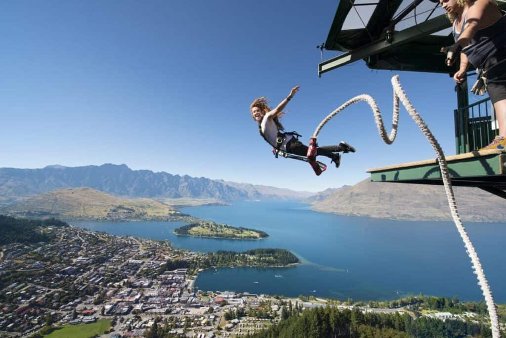 Woman bungee jumping from bridge over Queenstown, New Zealand with lake and mountains