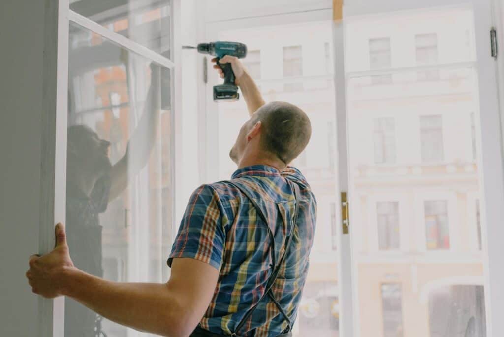 A Handyman Using a Drill on the Windows