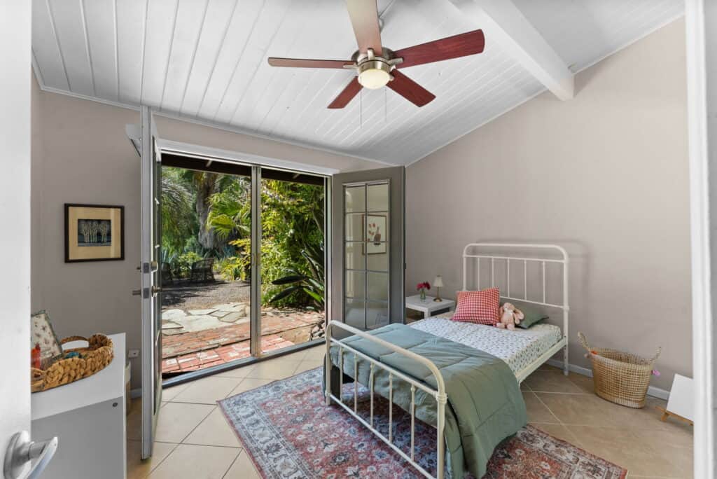large bedroom with grey bedding, and open french doors to outside