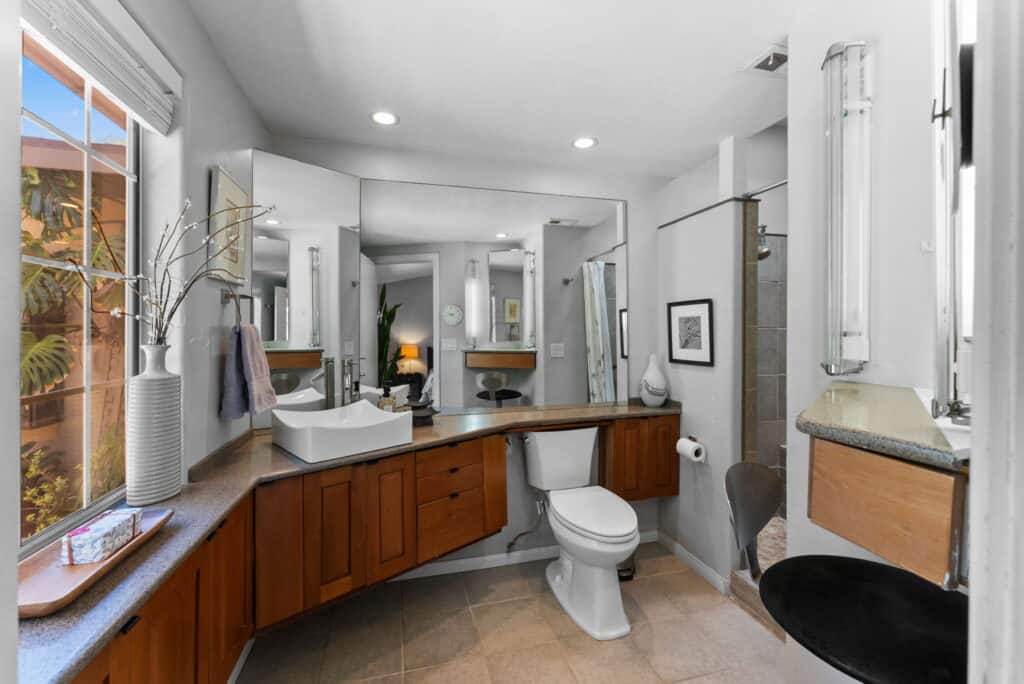 bathroom with brown cabinets, toilet and view of shower