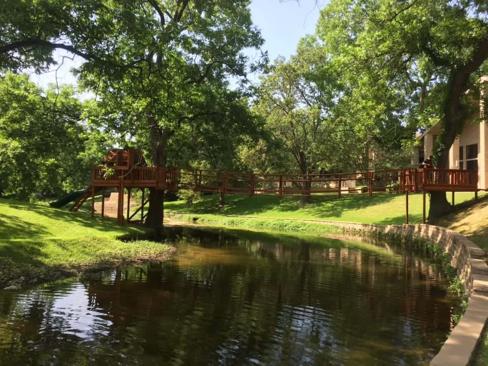unique playset spaces, redwood playset bridged to tree deck over creek in backyard