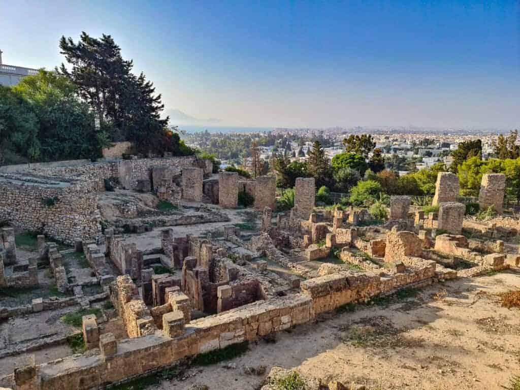 Elevated view of ancient stone ruins in Carthage with the city of Tunis in the background