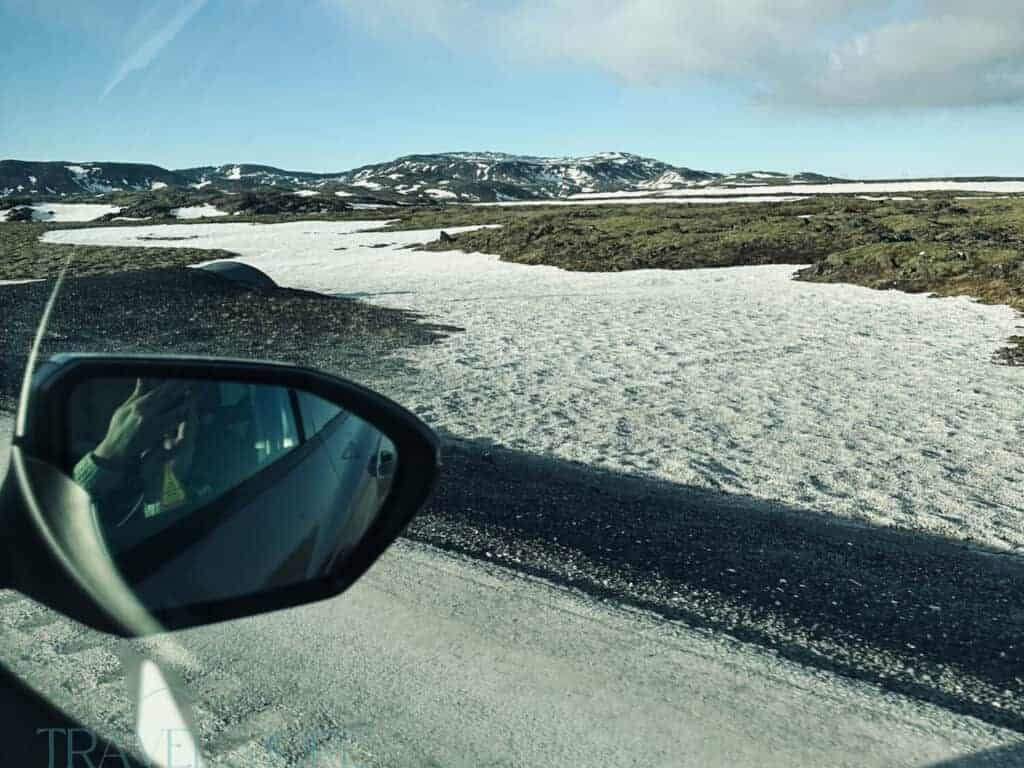 View from a car window of Iceland’s snowy volcanic landscape and mossy lava fields while driving along a rural road. Private Reykjavik airport transfers allow travelers to stop along scenic routes like this between Keflavik Airport and the capital.