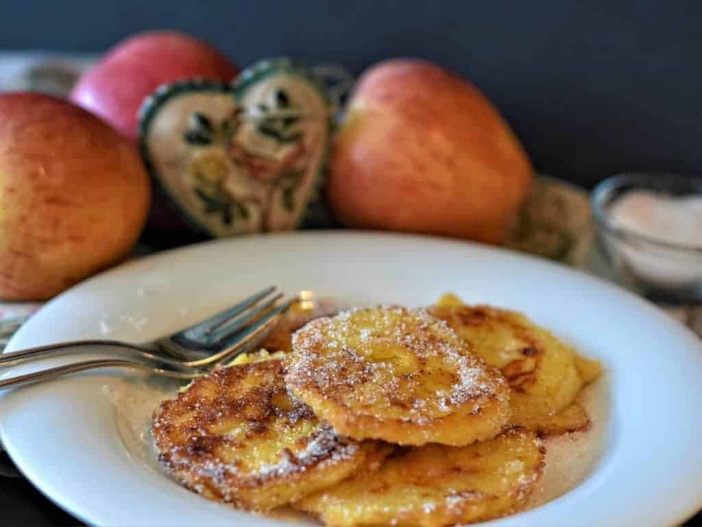 Polish racuchy pancakes in a white plate next to apples.