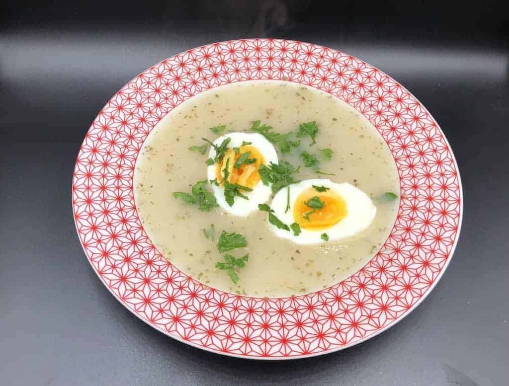 barszcz bialy white borscht soup in a red bowl.