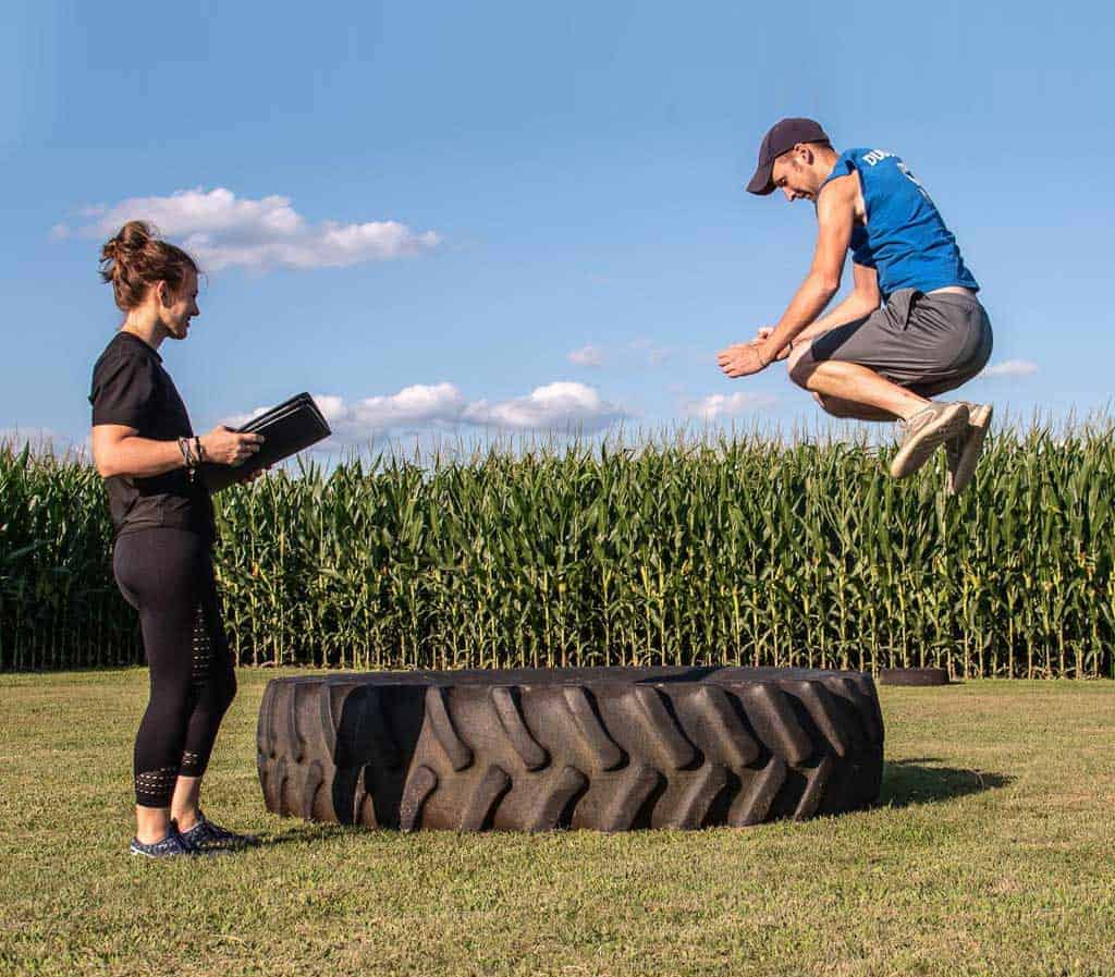 Man jumping over tire in personal training class.
