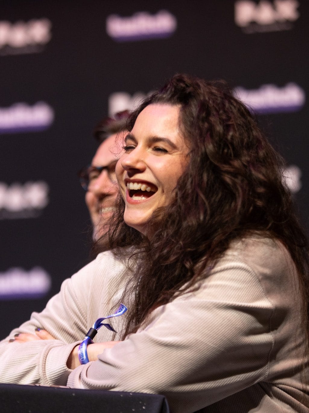 Australian accent female voice over talent with long brown curly hair laughing joyfully at a panel at PAX Australia