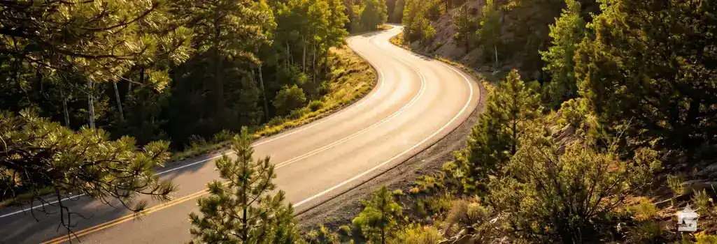 5 Steps to Take After a Motorcycle Accident in New Mexico 1 Golden hour sunlight illuminating a winding, empty mountain road through the Sangre de Cristo Mountains in Northern New Mexico.