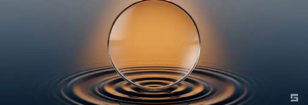 A clear glass lens focusing warm amber light over calm water ripples, representing clarity and expectations during a lawsuit. Legal process transparency and criminal defense resources from Grano Law Offices, P.C.