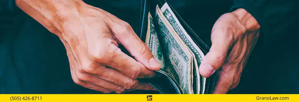 A person's hands opening a wallet and handling cash, representing the financial stakes of a legal case, with Grano Law Offices branding.