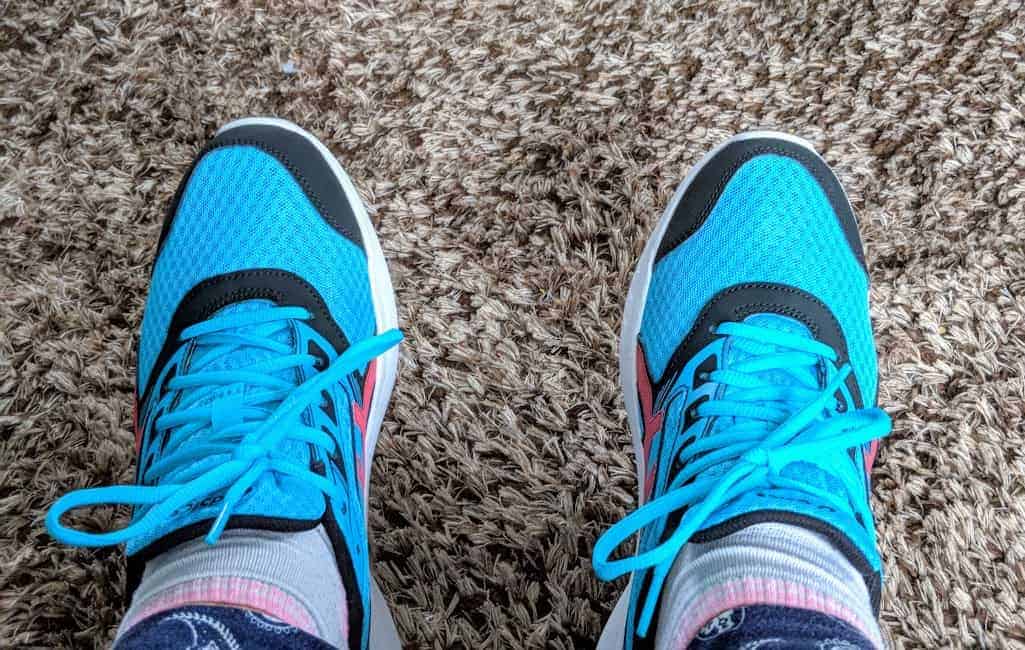 Pair of feet wearing blue shoes with black elements