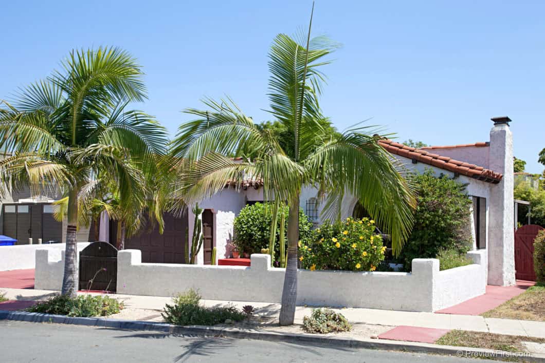 Spanish-style home with white stucco walls, a red clay tile roof, and palm trees at 3221 McKinley Street.