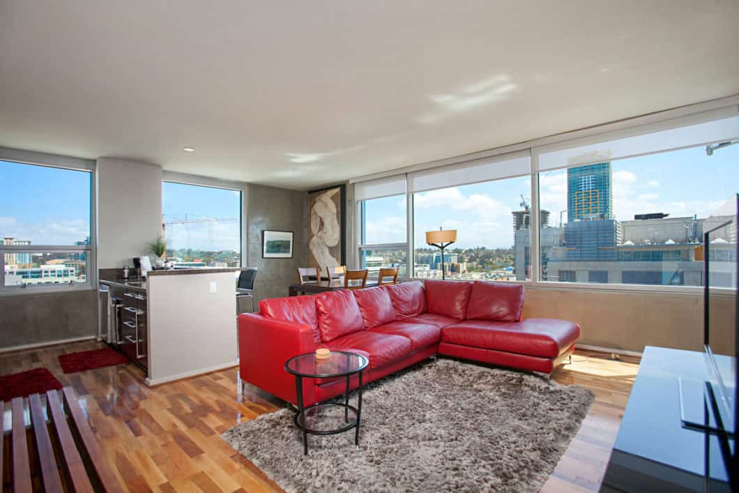 Open-concept condo at 321 10th Ave with panoramic city views, a red leather sectional sofa, and a modern kitchen with granite countertops.