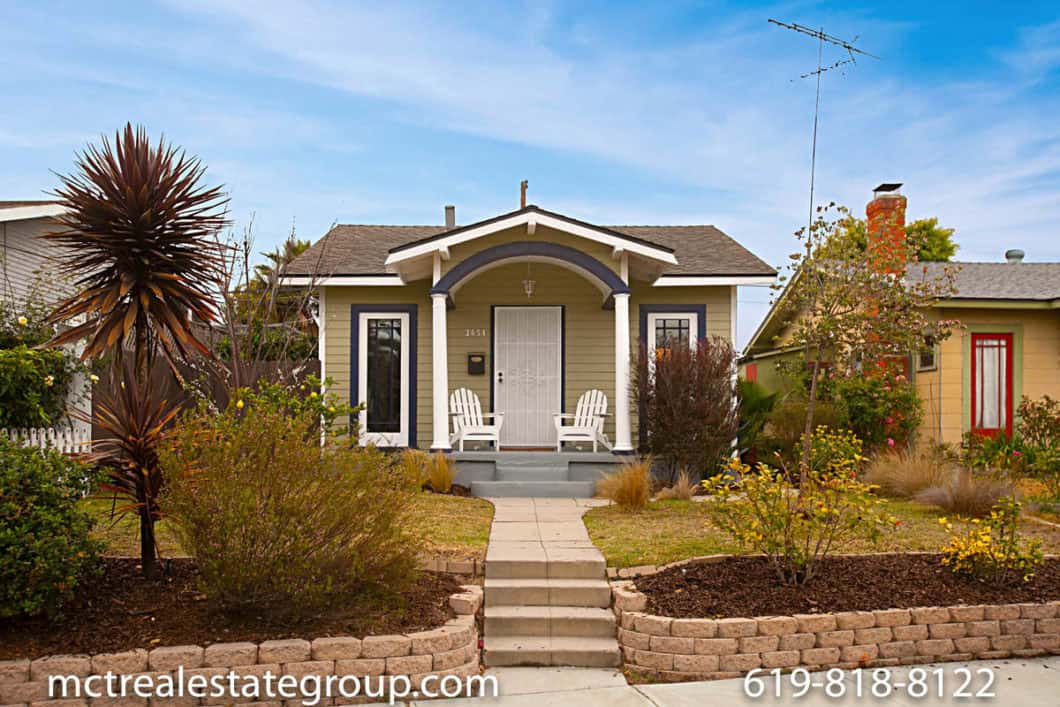Craftsman-style bungalow at 3654 Boundary Street in North Park featuring green siding, an arched front porch with white columns, two white chairs, and detailed front windows.