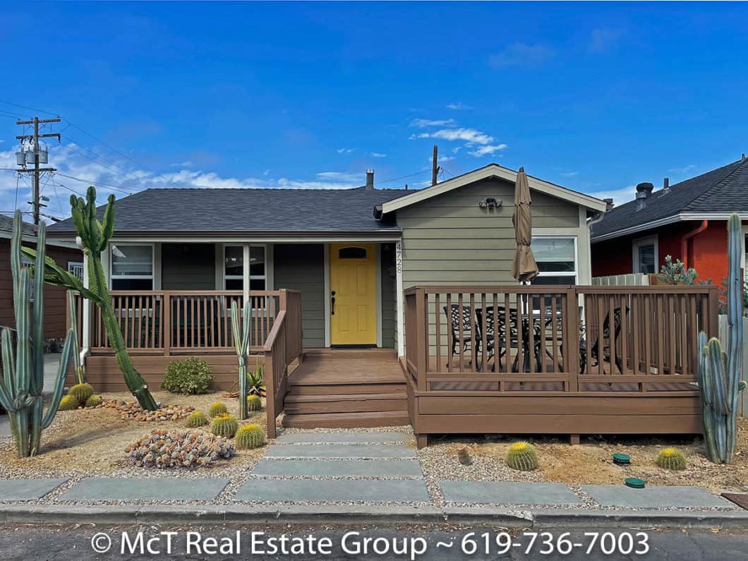 Front exterior of 4728 Works Place in University Heights featuring a yellow door, wooden deck, and drought-tolerant cactus landscaping.