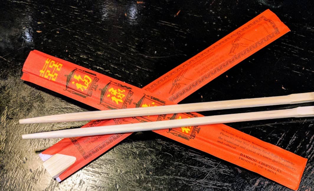 chopsticks lying on top of a red sleeve they came in