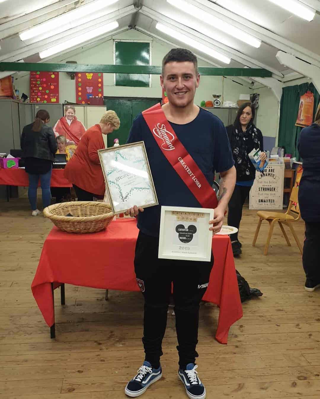 a man wearing a slimmer of the year sash at slimming world