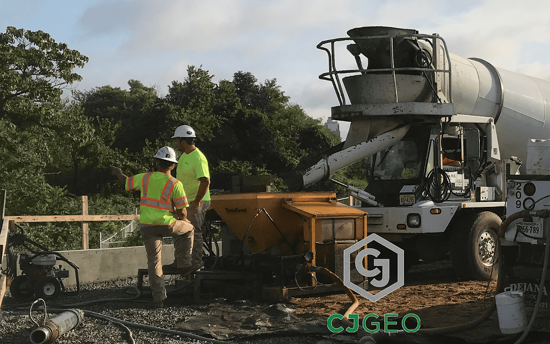 a front discharge ready mix truck discharging grout into a pump on a construction site