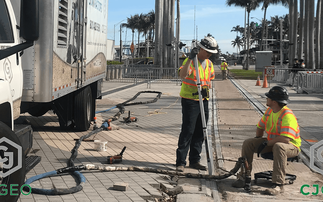 A CJGeo grouting truck sitting adjacent to a modular grade crossing with workers injecting polyurethane grout under the crossing panels.