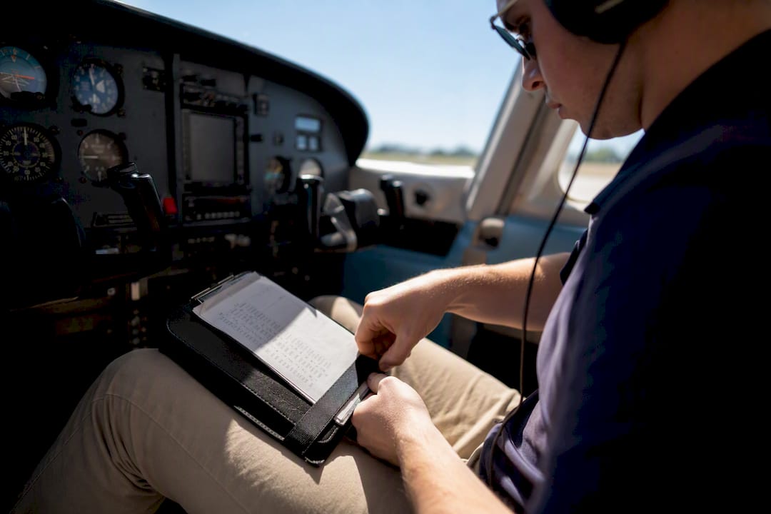 Pilot adjusting kneeboard inside training aircraft cockpit