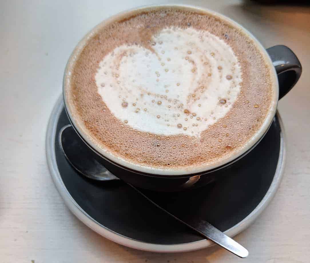 Hot chocolate in cup with heart design on top and teaspoon in saucer