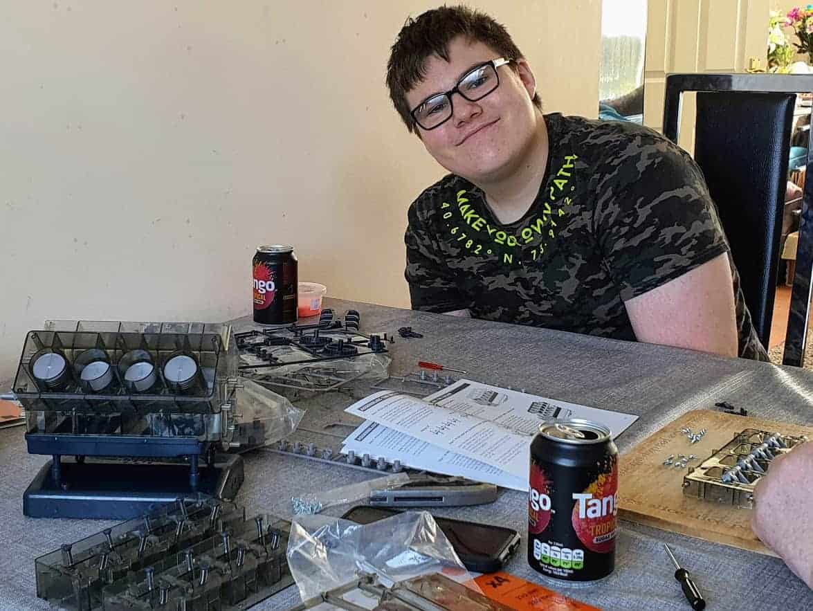 Ben smiling with parts of the half assembled engine in front of him