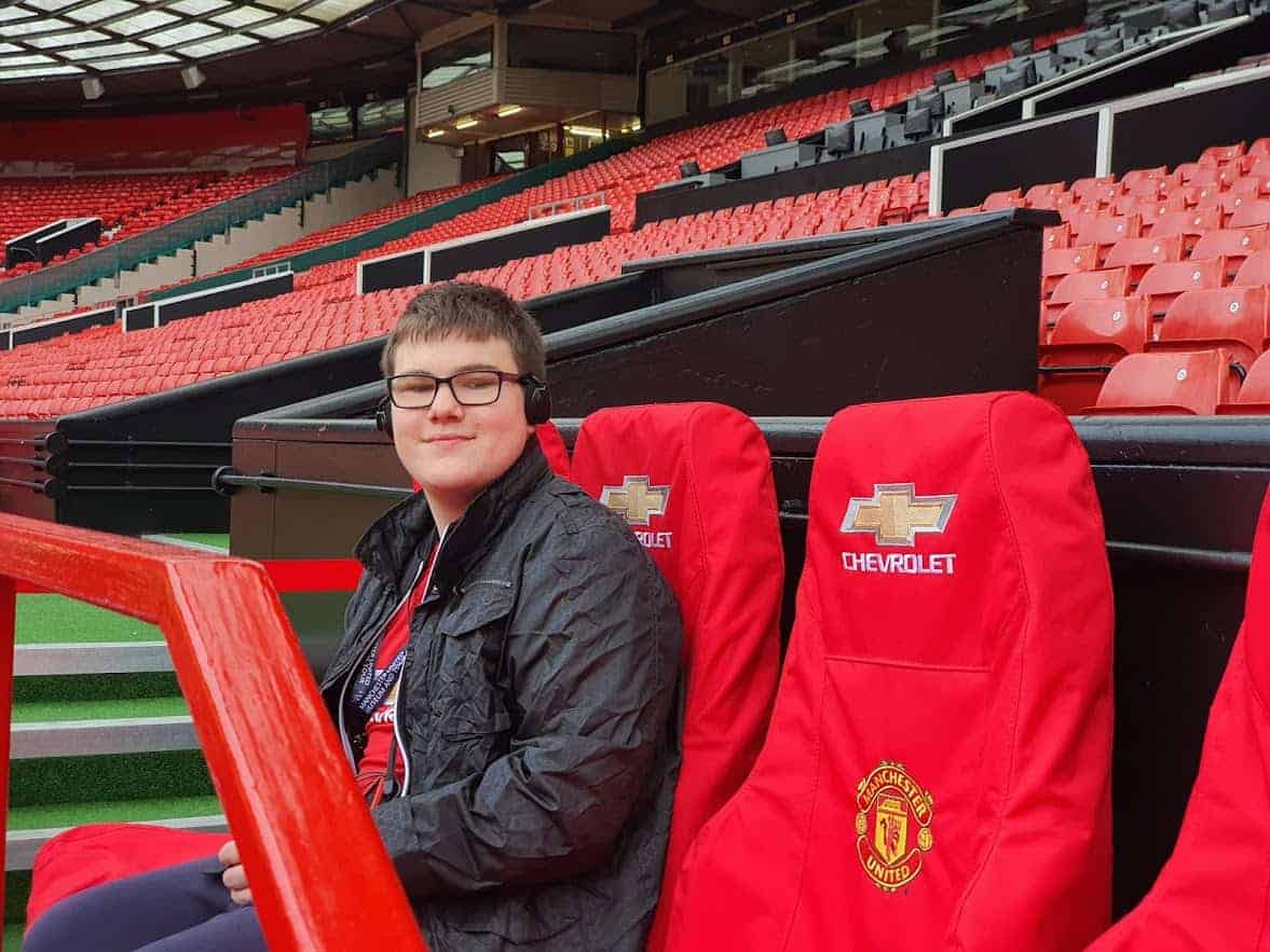 A young boy sitting in Manchester United seats at the stadium