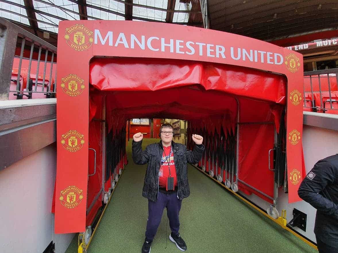 A young boy standing with a Manchester United sign