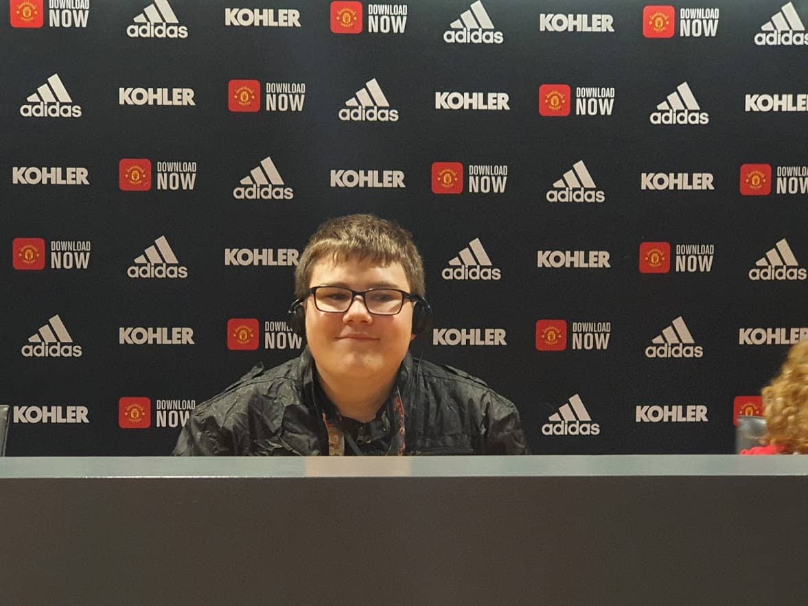 A young boy sitting at a desk at a football stadium