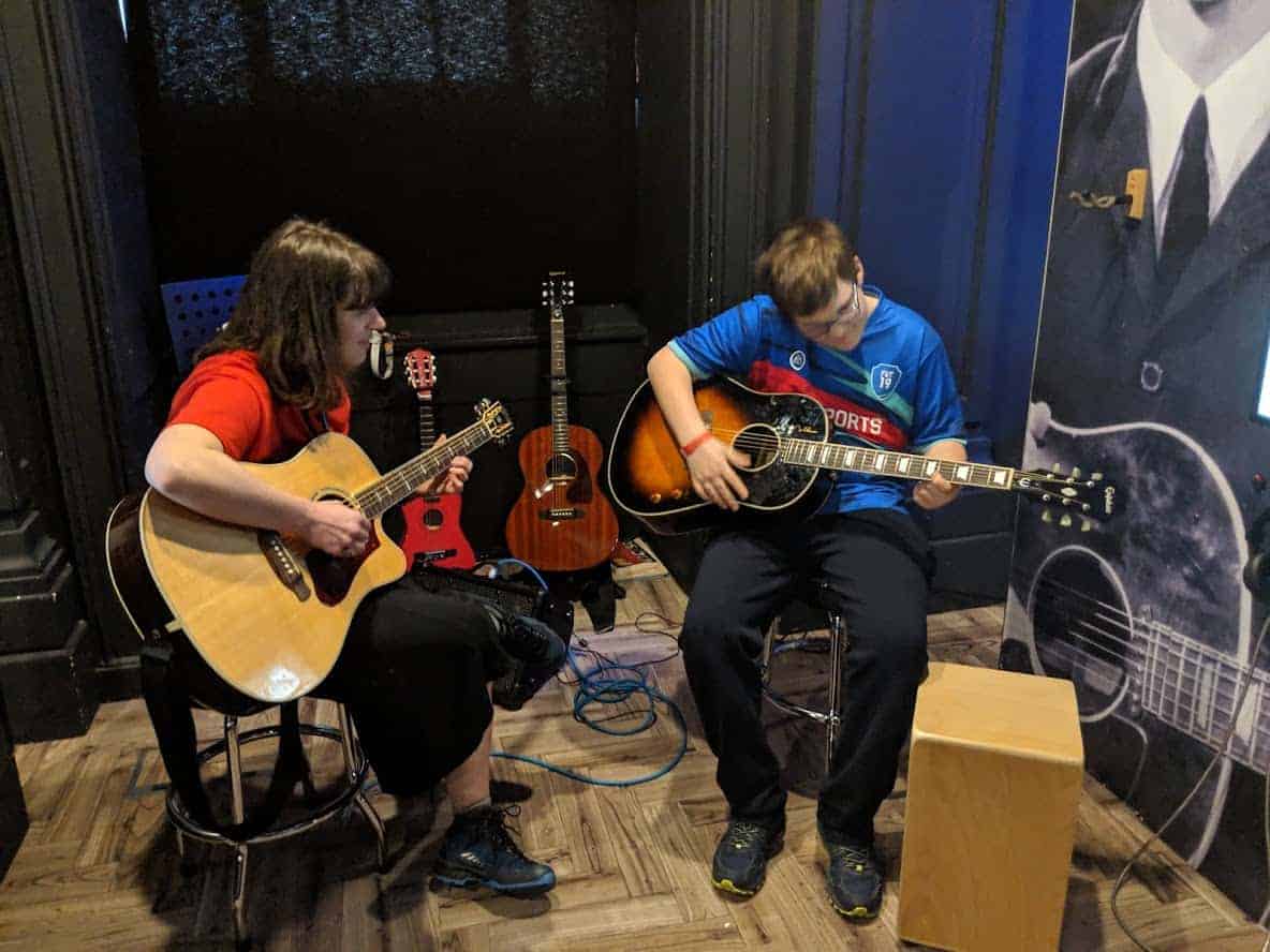 Two people sitting together playing guitar